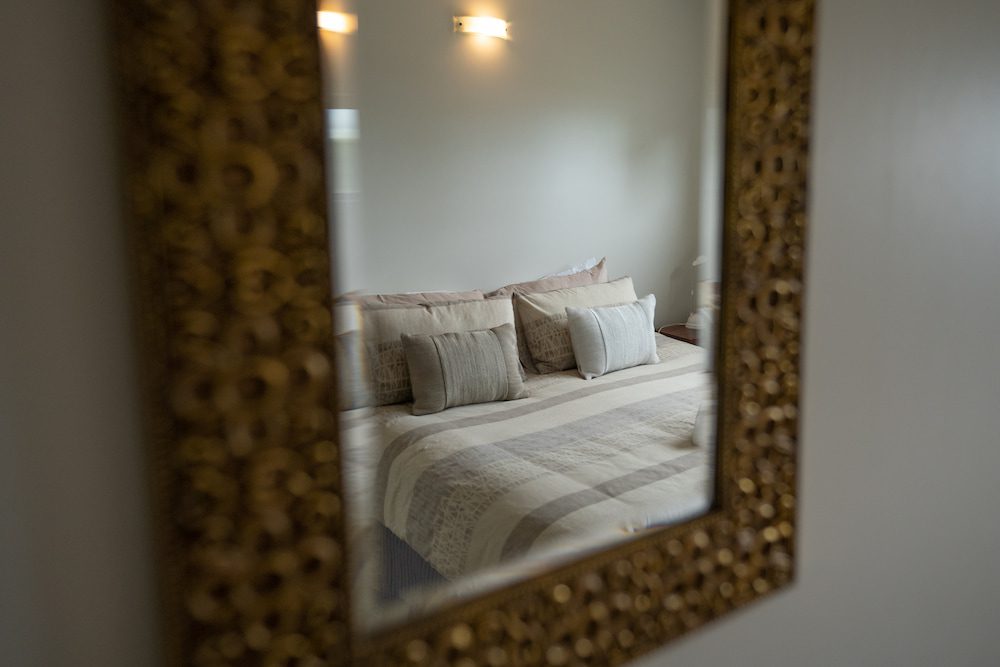 The reflection of a double bed in a wall mirror.