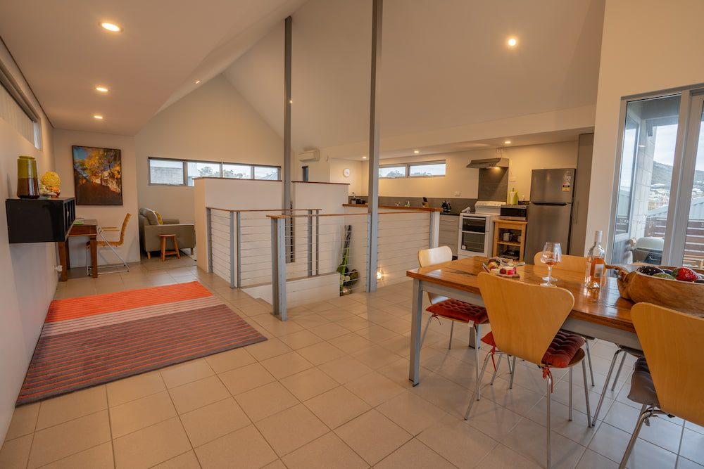 The upstairs area of the Lockyer Apartment with dining table, kitchen and stairwell.